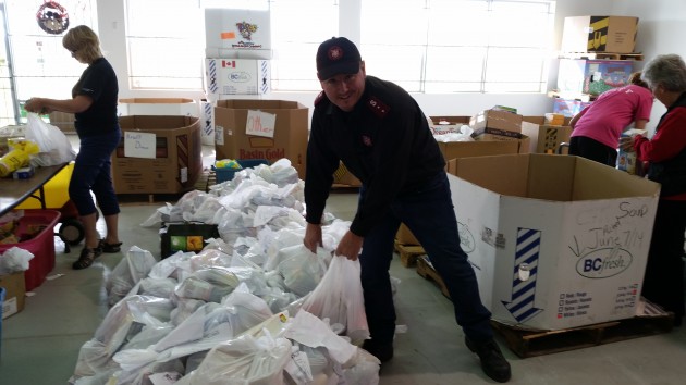 Captain Neil Wilkinson stands next to food donations - photo 250 News