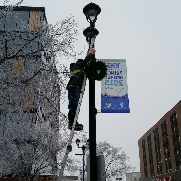 Robbie Richardson hangs basket at the corner of 5th Ave & George Street - photo 250 News