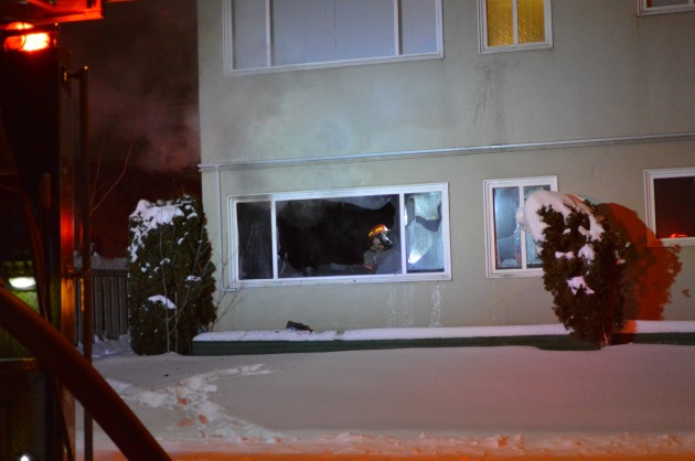 Firefighter checks for fire sources as smoke drifts out suite window. 250News photo