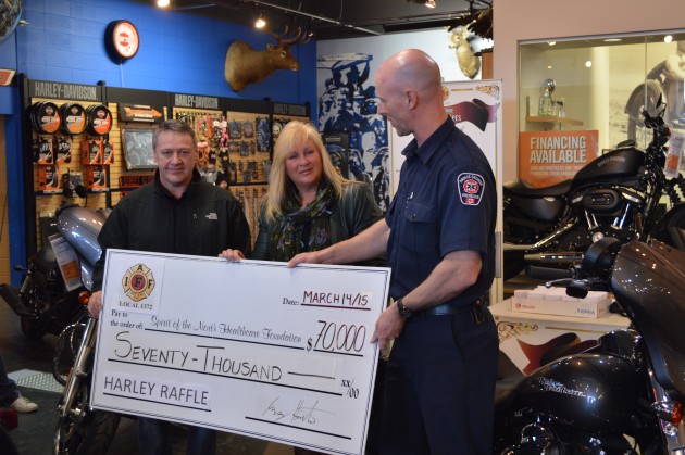Fire fighter Greg Houston presents cheque to Judy Neiser and Darcy Bryant of Spirit of North Healthcare Foundation. Photos 250 News