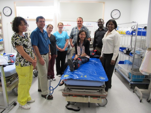 L-r Lab/x-ray tech Toni Cinnamon, Dr. S. Du Stephen de Toit, RNs Lisa Cox and Amber Flatt, Dr. Ray Markham, Dr Abimbola Olajide, Dr Folakemi Olajide and on spine board Med student Cynthia Kong.