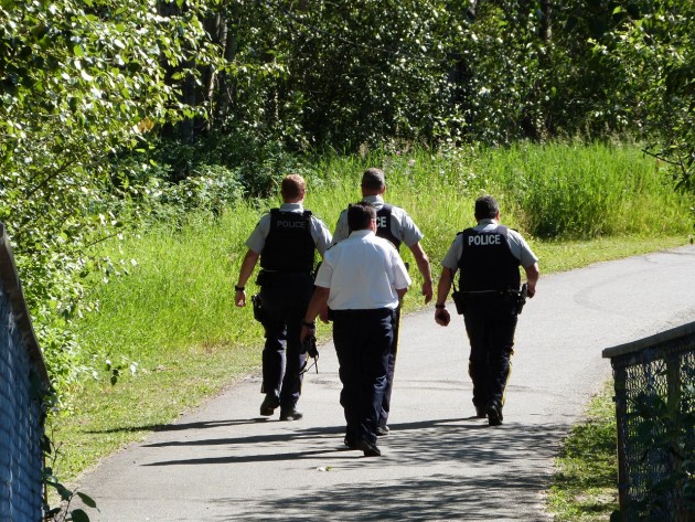 RCMP officers and ambulance paramedic cross bridge to south side of Hudson Bay slough. Photo 250News