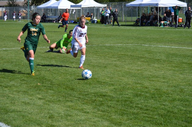 UNBC defender Fiona Raymond (14) recovers to clear after getting wires crossed with keeper Jordan Hall. Photo 250 News