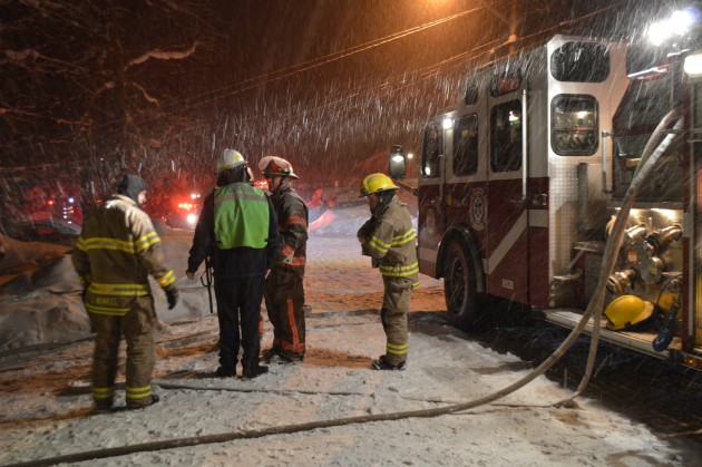 Assistant Chief Heaslip (green vest, white helmet) discusses fire and smoke damage.