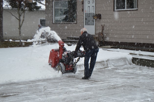 Resident clears his driveway following unexpected snowfall. Photos 250News