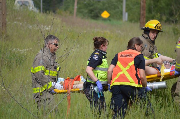 Paramedics and firefighters carry victim on stretcher to awaiting ambulance.