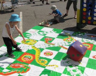 3 yr old Aiden Frenchcryderman tosses the dice in the Kids Zone Snakes and Ladders game