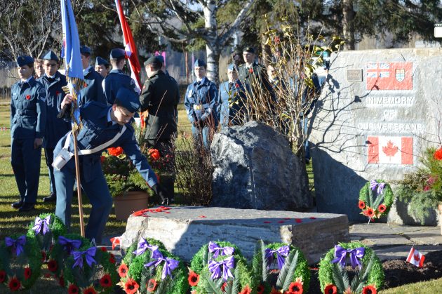 Aid cadet places poppy at foot of Veterans Memorial at ceremony held Sunday morning. Photo 250News