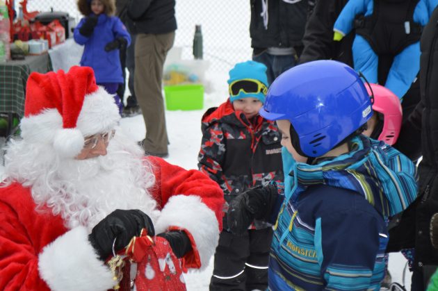 Youngsters look on with anticipation as Santa reaches into his bag of treats. Photos 250News